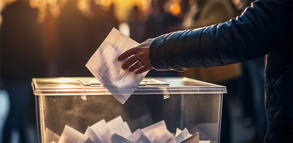 Eine Person die einen Wahlzettel in eine Wahlurne wirft